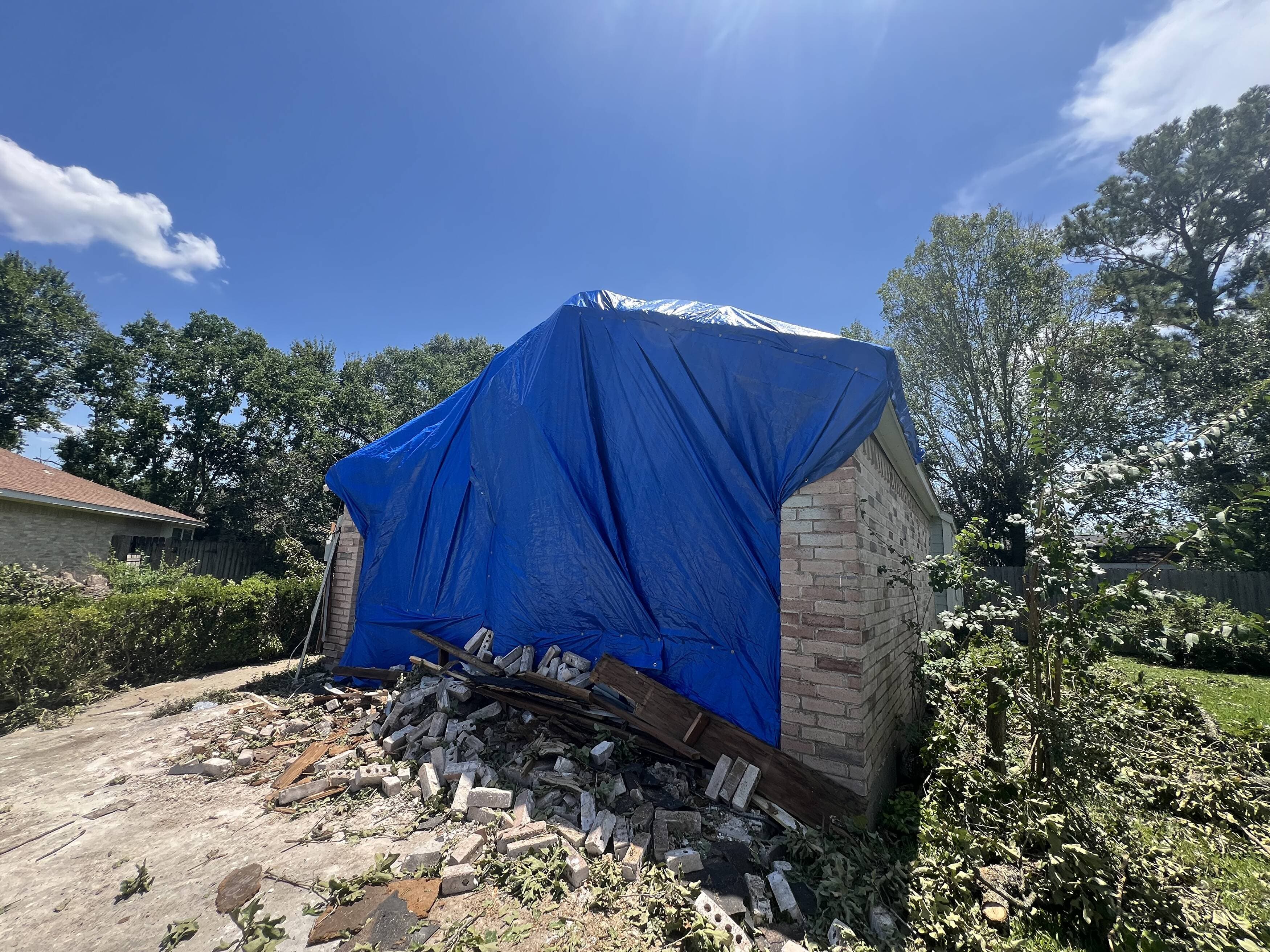 Emergency tarp secured over a storm-damaged garage by Roofing 365